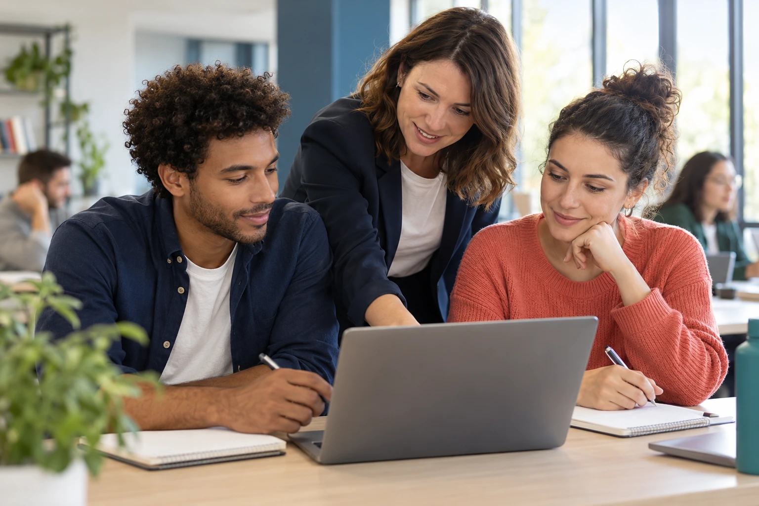 Adultes et formateur réunis autour d’un ordinateur dans un espace de formation professionnelle.